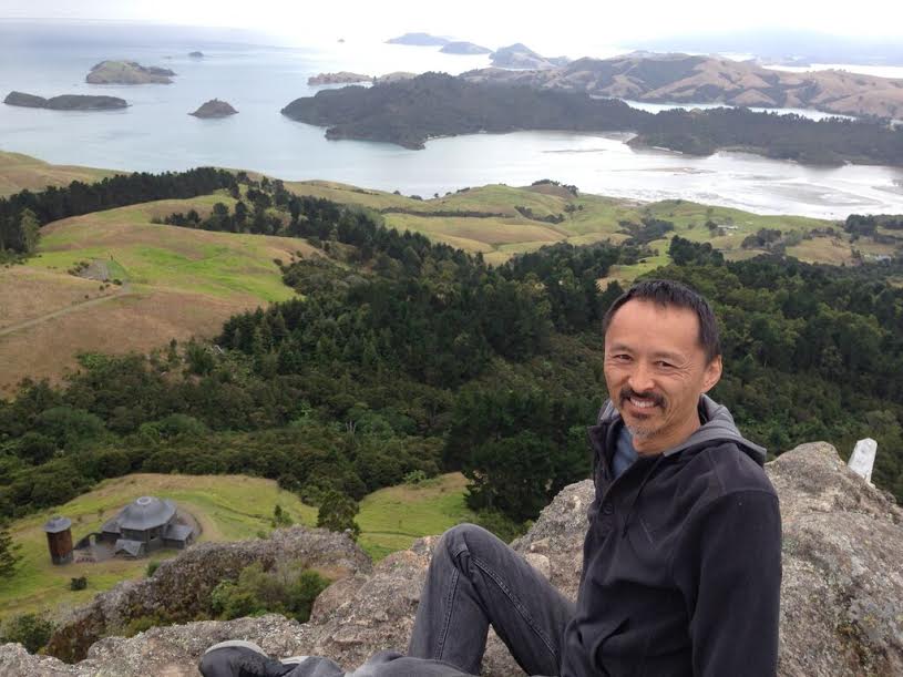 Darryl on top of a rock with a cave overlooking Mana Retreat Chapel